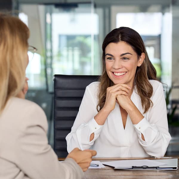 Happy mature professional business woman executive hr manager having job interview or business discussion with female applicant or colleague sitting at workplace in corporate office meeting.