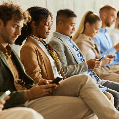 Diverse group of professionals sitting in a row at a conference or seminar, focused on taking notes and listening.