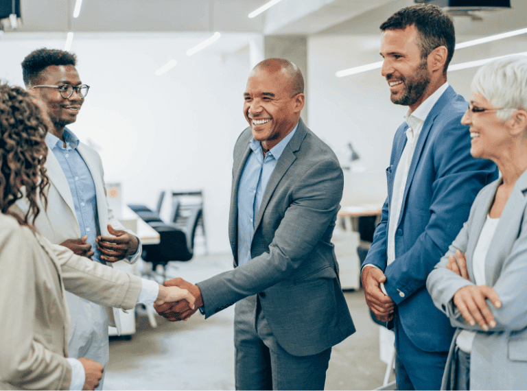 Diverse group of business professionals shaking hands and smiling in a modern office setting