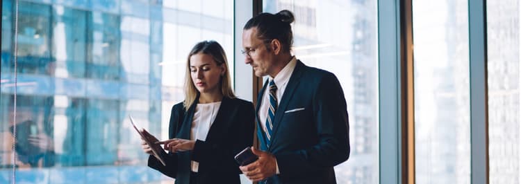 2 people standing by a window with an office background