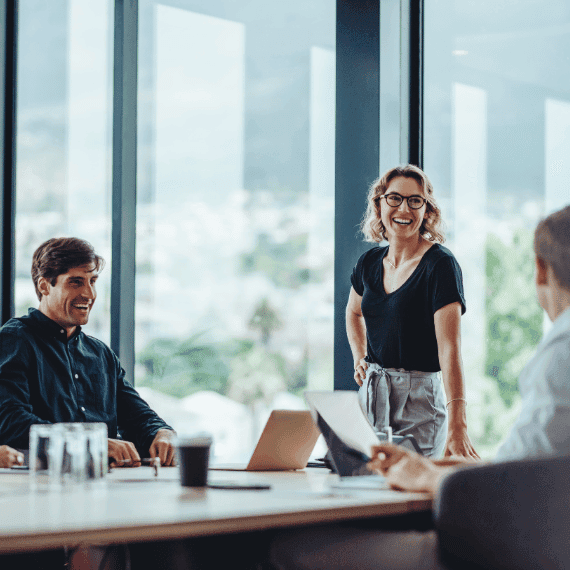 Business professionals collaborating in modern office meeting room with large windows and city view in background.