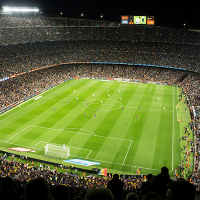 Aerial view of a packed World Cup stadium at night, with bright green field and crowds filling the stands.