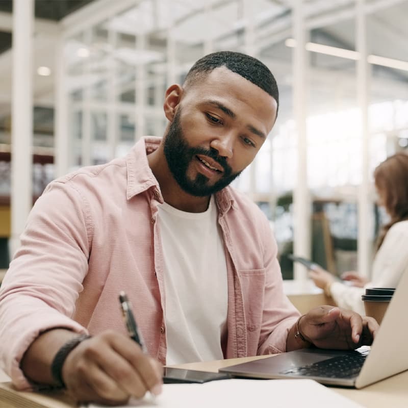 Writing, creative and man with laptop in office for business, project or research in startup. Computer, notes and African professional copywriter working on book for planning, web schedule and email.